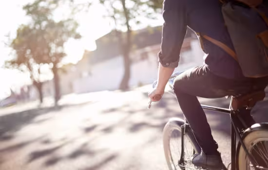 man som cyklar på gata i solljus med träd